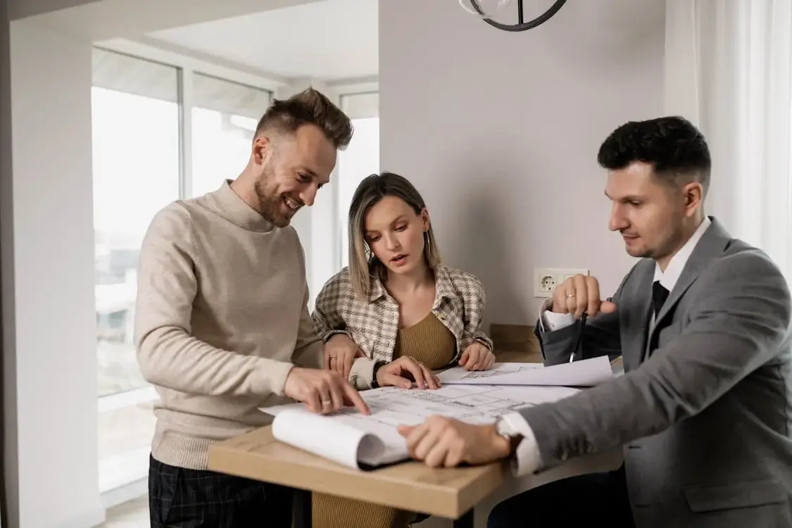 Couple reviewing property plans with a finance professional for investment insights.